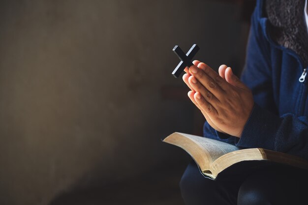 Hände gefaltet im Gebet auf einer heiligen Bibel im Kirchenkonzept für den Glauben