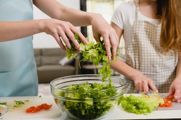 Hände gießen Gemüse für Salat in Schüssel