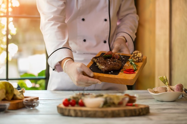 Hände halten Brett mit Fleisch.