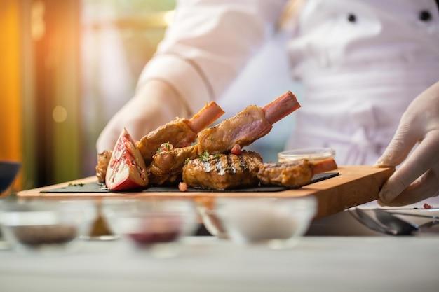 Hände halten Brett mit Fleischstück Granatapfel und Kräuter-Kalbsrippen serviert im besten Gericht des Restaurants...