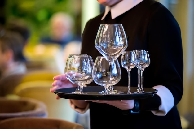 Hände halten ein Tablett mit Gläsern Kellner in einem Restaurant