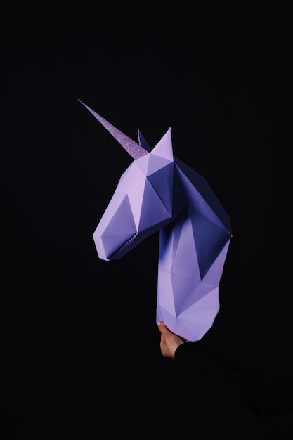 Hände halten ein türkisfarbenes Einhorn. Kunstwerk. Papiermodell 3d eines Einhorns. Kopieren Sie Platz