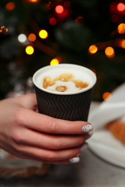 Hände halten eine heiße Tasse Kaffee. Kaffee zum Mitnehmen im Winter.