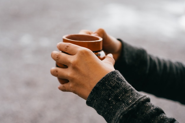 Hände halten eine Tasse Café de Olla, traditionell aus Mexiko.