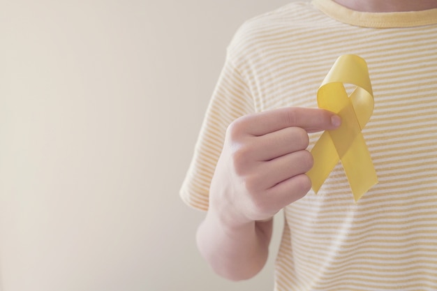 Hände halten Gelbgoldband, Sarkombewusstsein, Krebsbewusstsein bei Kindern, Konzept des Welt-Suizidpräventionstages