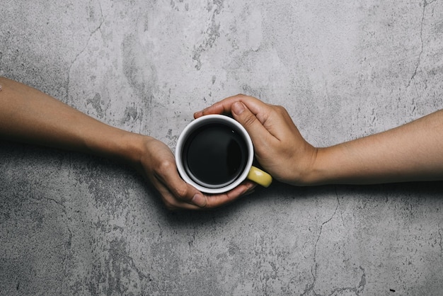 Hände halten Kaffeegetränk auf Tasse isoliert auf grauem Hintergrund, Ansicht von oben.
