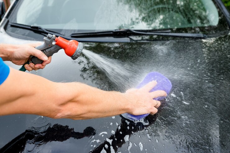 Hände halten Schwamm zum Waschen des Autos.