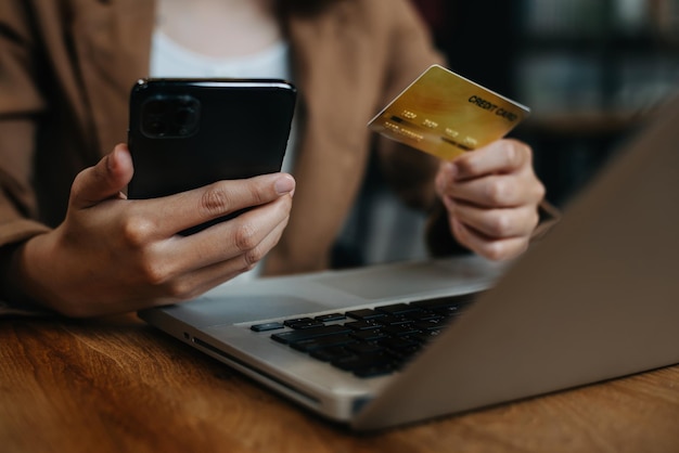 Hände halten Smartphone und Kreditkarte im Home Office Online-Shopping