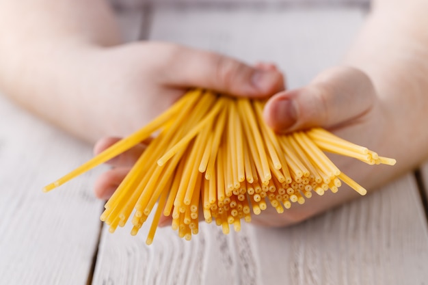 Hände halten Spaghetti in der Küche