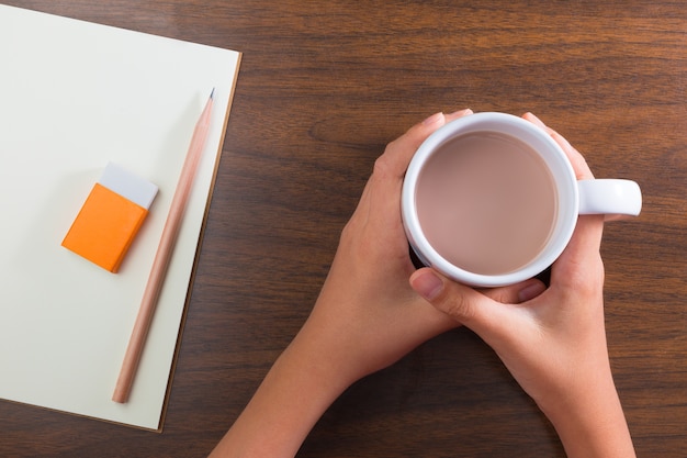 Hände halten Tasse heißes Getränk und stationär auf dem Tisch