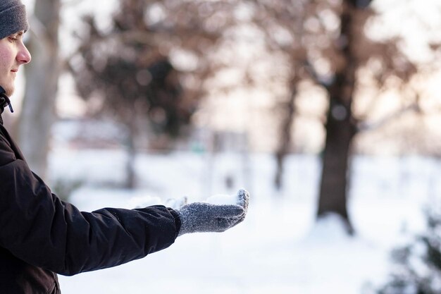 Hände in grauen Winterhandschuhen Palme mit einem Handschuh im Schnee Der Typ warf Schnee