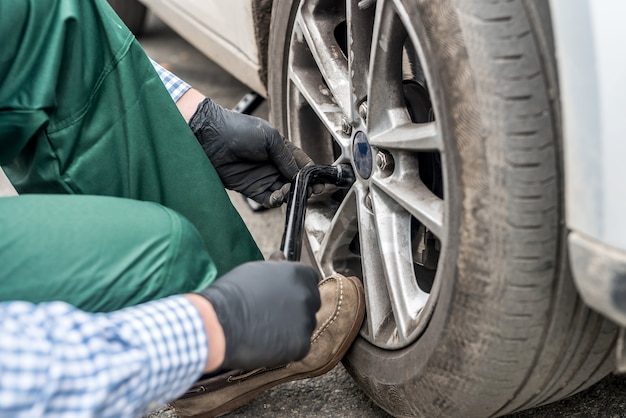 Hände in Handschuhen, die Muttern an der Nahaufnahme des Autorades befestigen