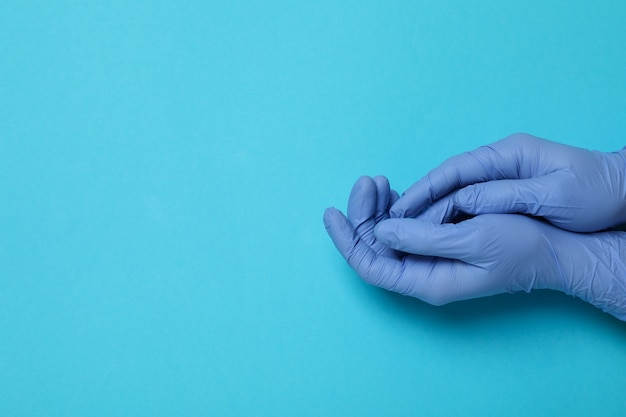 Hände in medizinischen Handschuhen auf blau