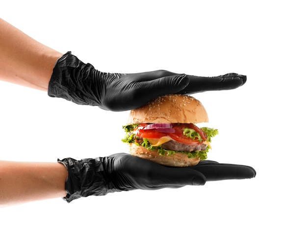 Hände in schwarzen Handschuhen halten einen saftigen, appetitlichen Beef-Burger auf weißem Hintergrund. Hamburger in den Händen isoliert. Banner für Fast-Food-Werbung