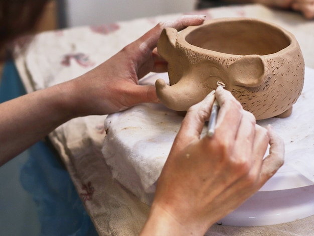 Hände in Ton machen eine Keramikschale