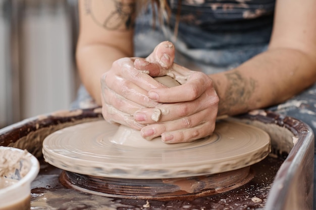 Hände junger kreativer Frauen, die in der Werkstatt eine Töpferscheibe drehen