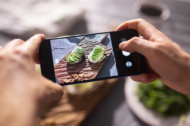 Hände machen Fotos von gesunder Sauerrahm auf dem Smartphone