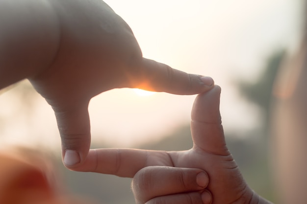 Hände machen Rahmenform sehen Silhouette schönen Sonnenuntergang Hintergrund.