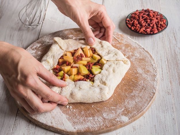 Hände machen Teig Apfelkuchen oder Goji Beere. Apfelkuchen für den Urlaub.