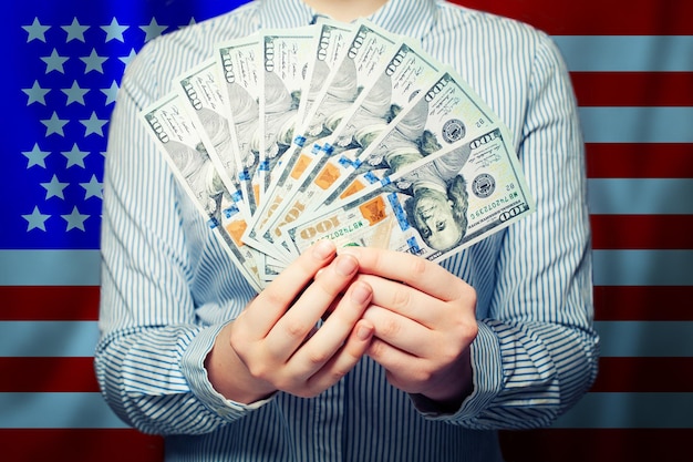 Foto hände mit bargeld, us-dollar-banknoten mit amerikanischer flagge im hintergrund