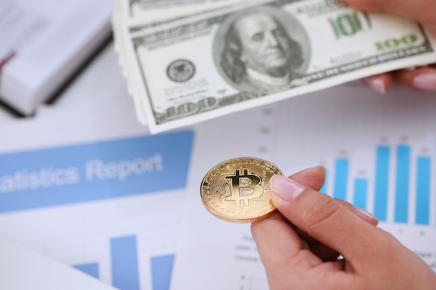Hände mit Bitcoin und Fan von Dollars