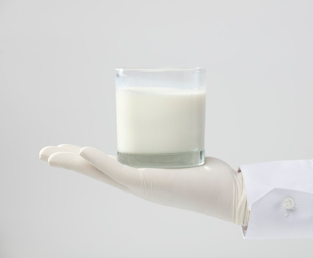 Hände mit Handschuh halten ein Glas Milch