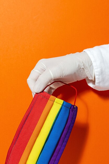 Hände mit Handschuhen, die hausgemachte Mode zeigen und LGBT-Masken für den Schutz vor Covid-19 entwerfen