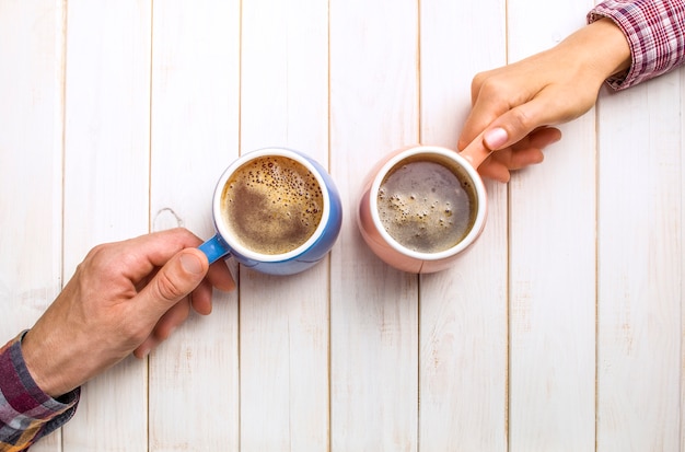 Hände mit Kaffee auf dem Tisch. Frühstück für zwei