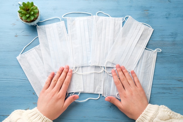 Hände mit medizinischen Masken auf einem blauen Tisch