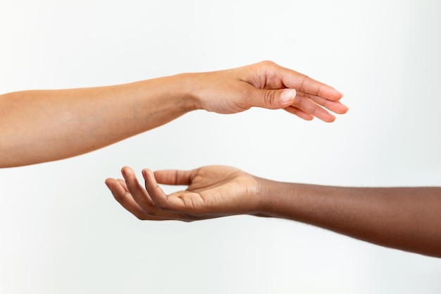 Foto hände mit unterschiedlicher hautfarbe, ein afroamerikaner, ein kaukasier, der sich auf grauem hintergrund berührt