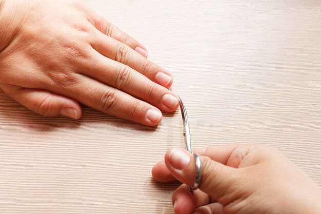 Hände Nahaufnahme, ein Mädchen, das sich eine Maniküre macht, Nagelschere.