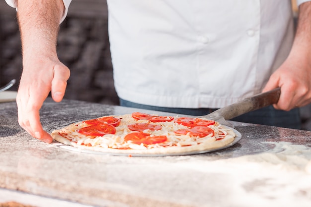 Hände nehmen eine Pizza vom Tisch