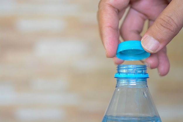 Hände öffnen sanft die Kappe einer erfrischenden Wasserflasche, die bereit ist, den Durst zu löschen