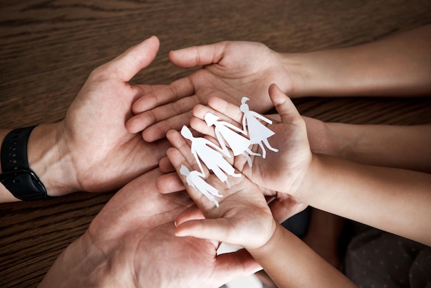 Foto hände papierausschnitt familie und haus auf dem tisch für zeichensymbol oder ikone der unterstützung, liebe und solidarität kunstdesign mit mutter, vater und kindern zusammen für sicherheit, vertrauen und versicherung zu hause