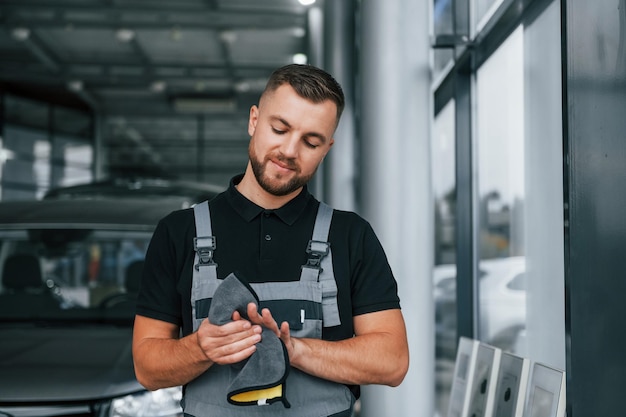 Hände reinigen Mann in Uniform arbeitet tagsüber im Autosalon