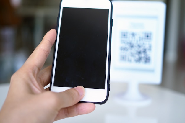 Hände scannen mit dem Telefon QR-Codes, um Rabatte auf Einkäufe zu erhalten.