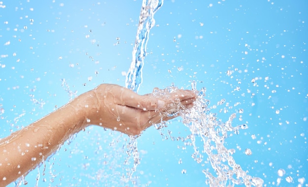 Hände spritzen Wasser und reinigen Hautbakterien und Hygiene für blauen Studiohintergrund mit Mockup-Platz Handspülwäsche oder Reinigung für frische hygienische Reinigung oder Hydratation in der Hautpflege