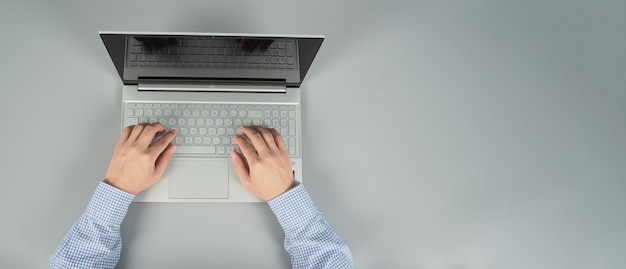 Hände tippen und Computer Laptop oder Notebook auf grauem Hintergrund. Studio shot.top Augenansicht.