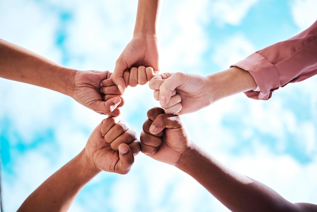 Foto hände und faust der menschen stoßen in zusammenarbeit, vertrauen oder einheit für partnerschaft, gemeinschaft oder vielfalt mit dem himmel darunter. verschiedene gruppen berühren sich die hände für teamerfolg oder motivation in solidarität