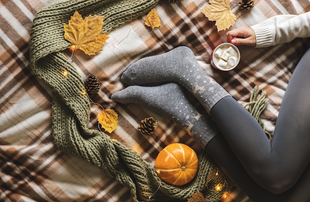 Hände und Füße der Frauen in den woolen grauen Socken, die Schale heißen Kaffee mit Eibisch halten