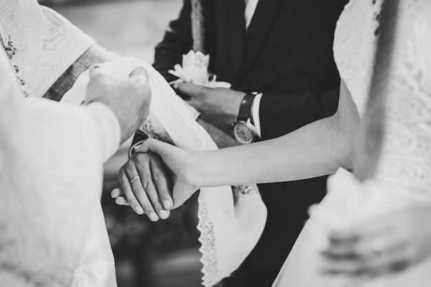 Foto hände von braut und bräutigam gebunden hochzeitstuch der priester bindet das handtuch der braut hände junger paare in der kirche hochzeitstag schwarz-weiß-foto