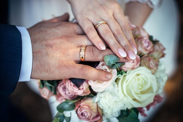 Hände von Braut und Bräutigam mit goldenen Ringen auf einem Vintage-Hochzeitsstrauß Nahaufnahme Konzept eines glücklichen Hochzeitstages