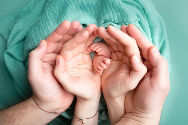 Hände von Eltern und Kindern auf weißem Hintergrund Beine eines Neugeborenen in den Händen von Mama und Papa