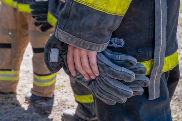 Hände von Feuerwehrleuten mit Handschuhen an den Händen