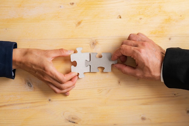 Hände von Geschäfts- und Geschäftsfraupartnern, die zwei leere passende Puzzleteile verbinden