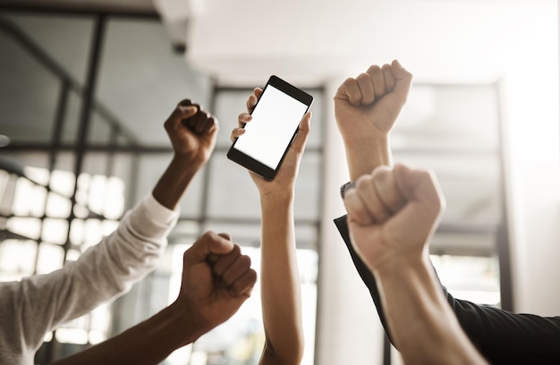 Hände von Geschäftsleuten jubeln, um gute Nachrichten auf einem Telefon mit leerem Bildschirm für Kopierplatz zu feiern Aufgeregtes Team von Büroangestellten, die eine Power-Faust-Geste für den Sieg und den Sieg zeigen