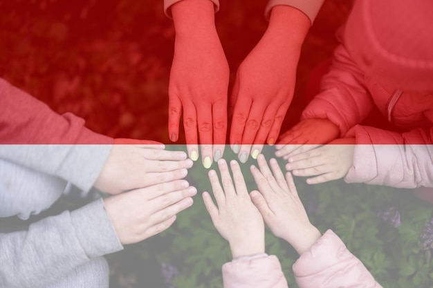 Hände von Kindern auf dem Hintergrund der indonesischen Flagge Indonesischer Patriotismus und Einheitskonzept