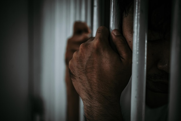Hände von Männern, die verzweifelt versuchen, das Konzept der eisernen Gefängnisgefangenen zu fangen, hoffen, frei zu sein