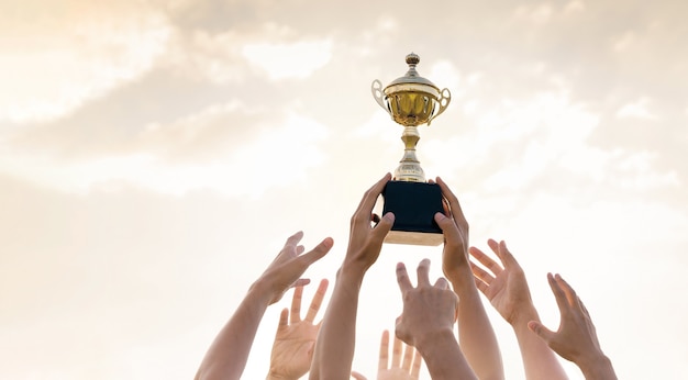 Hände von Menschen mit goldenem Trophäen-, Sport- und Geschäftswettbewerbskonzept.