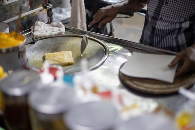 Hände von Straßenverkäufern, die süßes Roti-Brot im thailändischen Stil auf Stahl-Roti-Pfanne oder großer flacher Bratpfanne kochen. Genießen Sie Thailands Streetfood.